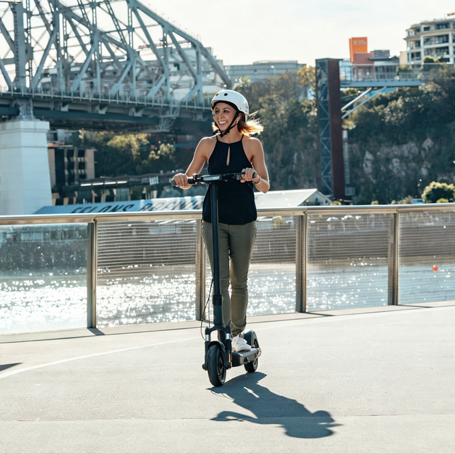Smiling person on electric scooter by river