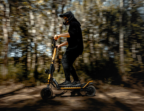 Person riding electric scooter through forest trail