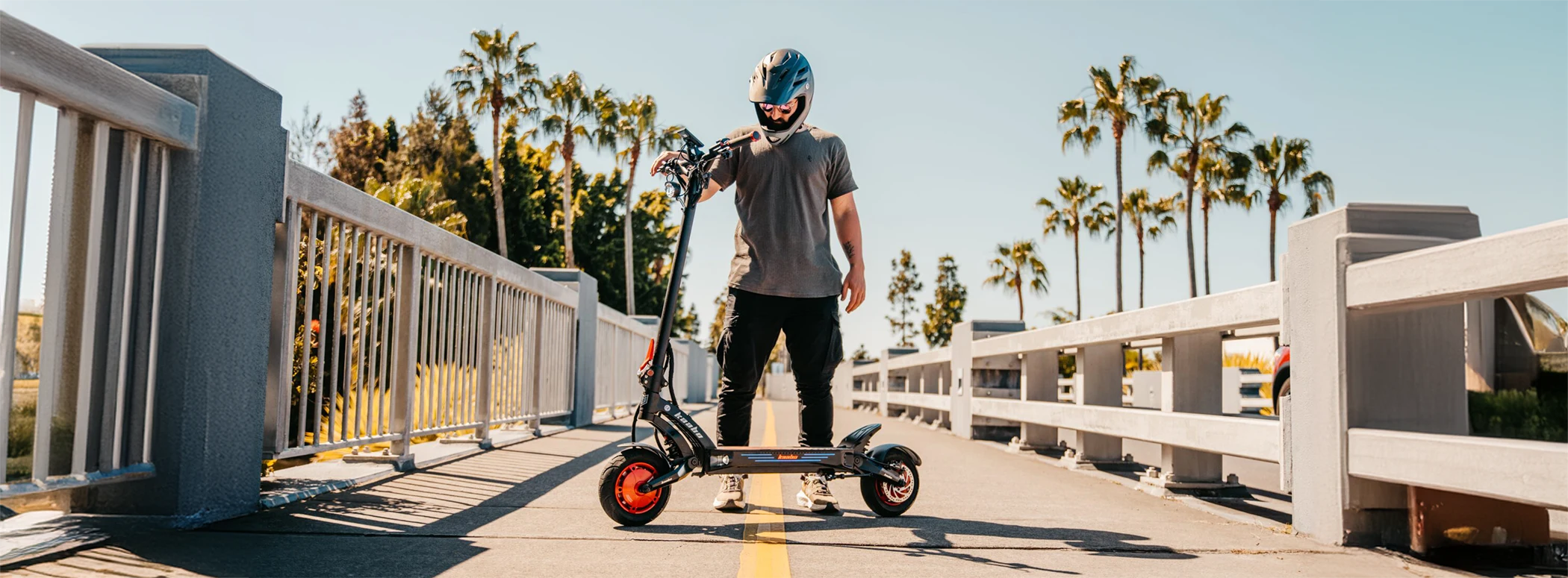 Person holding electric scooter on sunny bridge